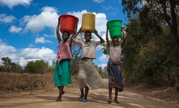 Girls carrying water buckets at a borehole in Malawi
