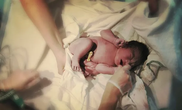High angle view of newborn baby with nurses in hospital