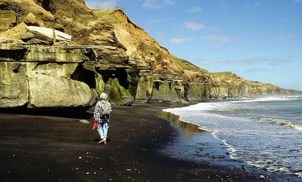 Black iron sands, Geologist at base of muddy sand siltstones, South Taranaki coast, New Zealand