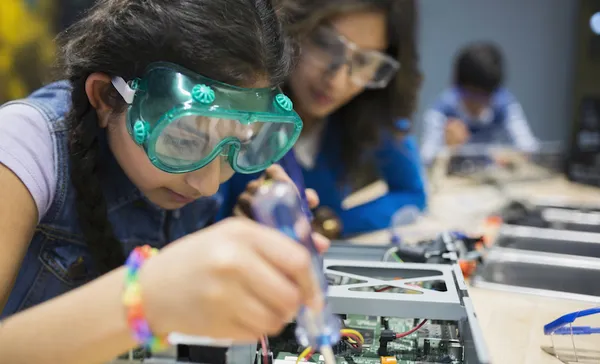 Mother watching daughter assembling electronics at science center