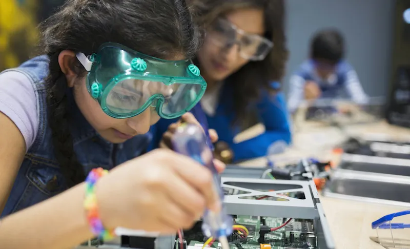Mother watching daughter assembling electronics at science center