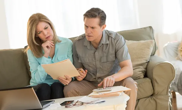 Mature couple calculating home finances on sofa