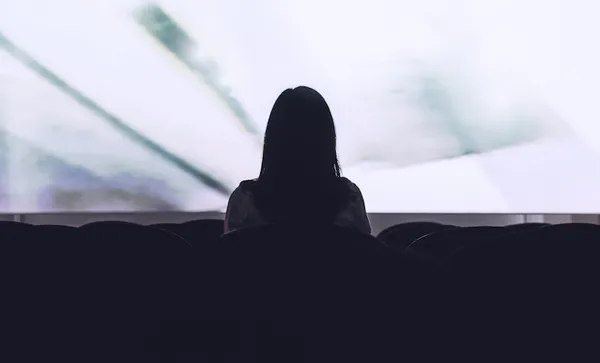 Rear view of woman sitting alone watching movie in empty theatre