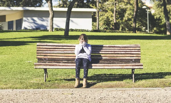Girl sitting alone on a park bench