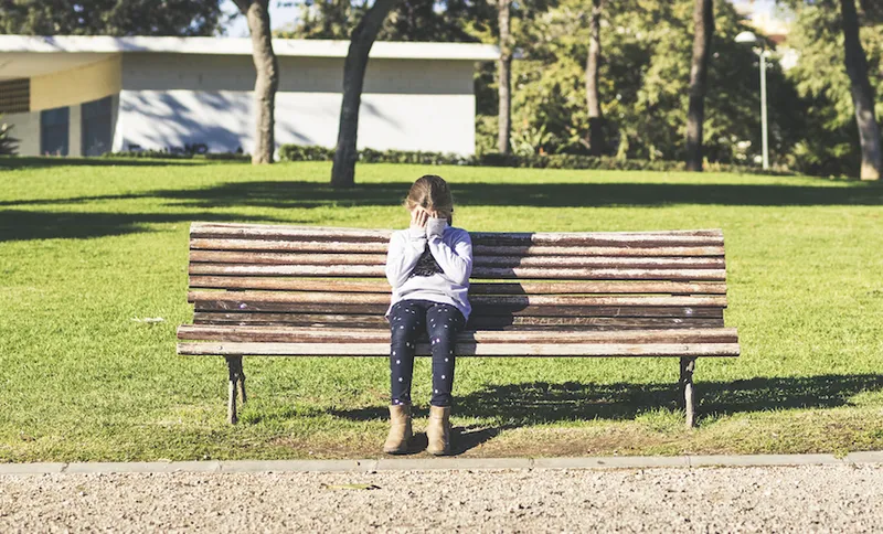 Girl sitting alone on a park bench