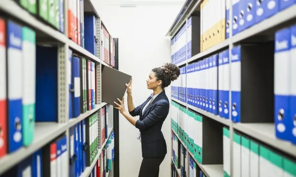 Woman is searching for files in paper archive