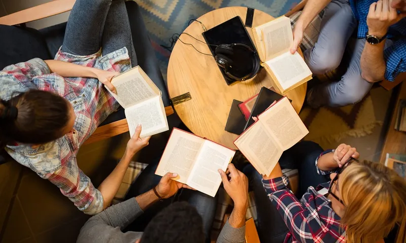 Diverse group of friends discussing a book in library.