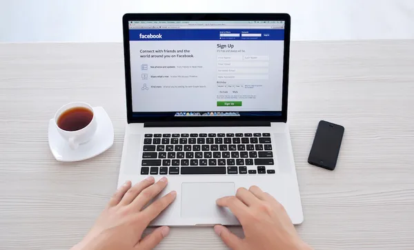 man sitting at the MacBook retina with site Facebook on the screen