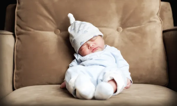 Baby boy asleep on arm chair