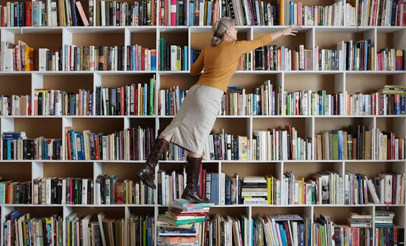 Older woman standing on stack of books