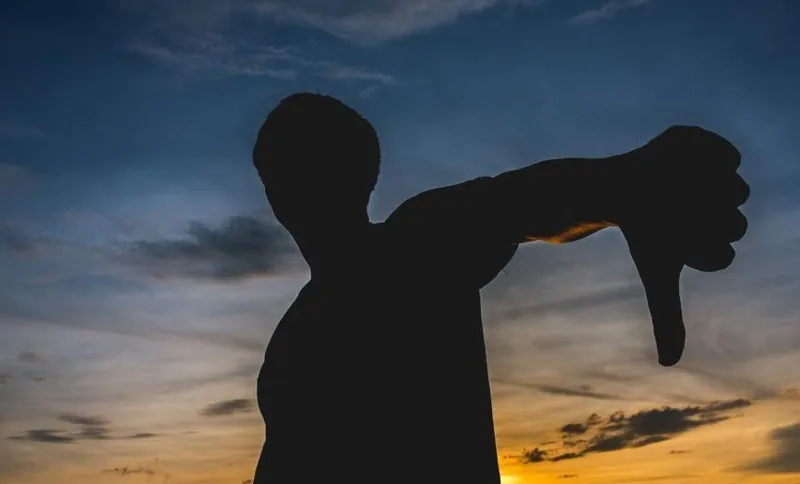 Silhouette Man Gesturing Thumbs Down Against Sky During Sunset