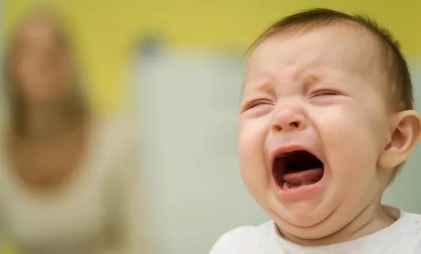 Baby crying, mother in background