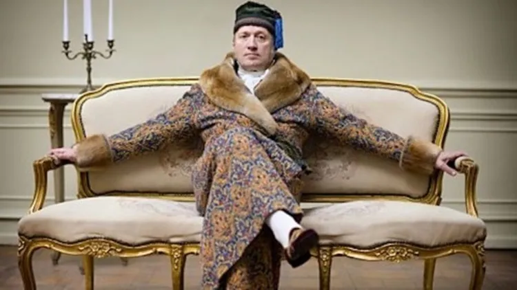 Adrian Edmondson in robe and smoking cap. With a tassel of course.