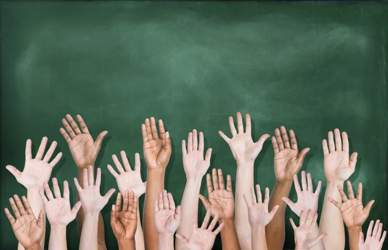 Multiethnic Group of Hands Raised with Blackboard