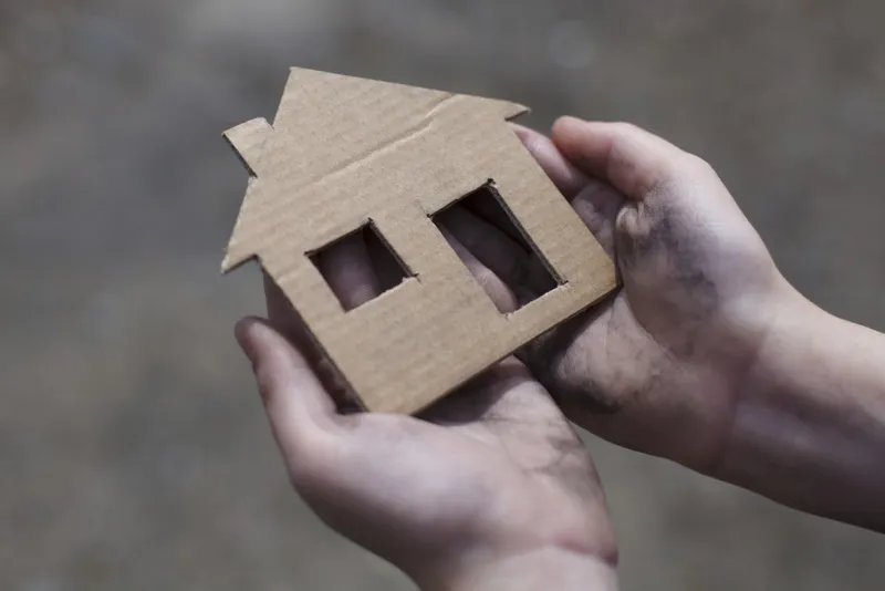 homeless boy holding a cardboard house, dirty hand