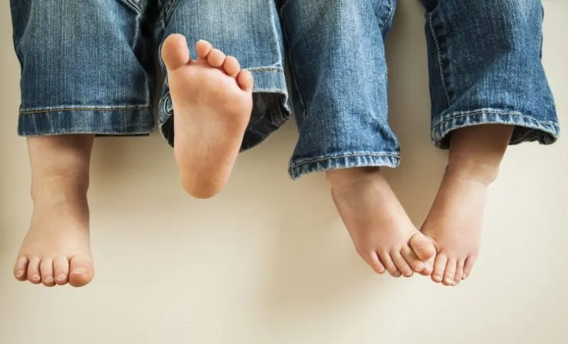 Two children's legs wearing jeans swinging feet.