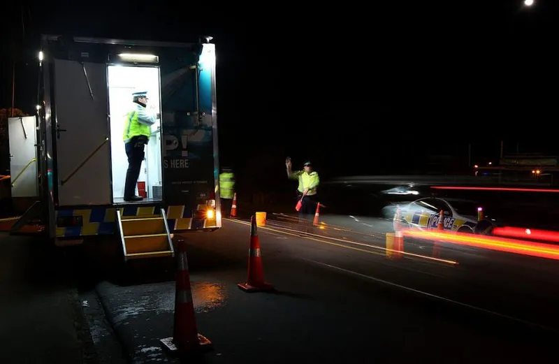 AUCKLAND, NEW ZEALAND - JULY 30: A police officer stops a motorist at a drink driving check point in Penrose on July 30, 2010 in Auckland, New Zealand. The government is implementing a zero-tolerance policy for drivers under 20 and repeat drink-drivers, but will conduct more research before deciding whether to lower the adult alcohol limit from 0.08g of alcohol per 100ml to 0.05g. (Photo by Sandra Mu/Getty Images)