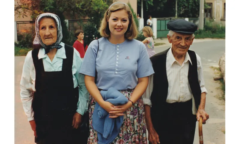 An old photo of a young woman flanked by two elderly people.