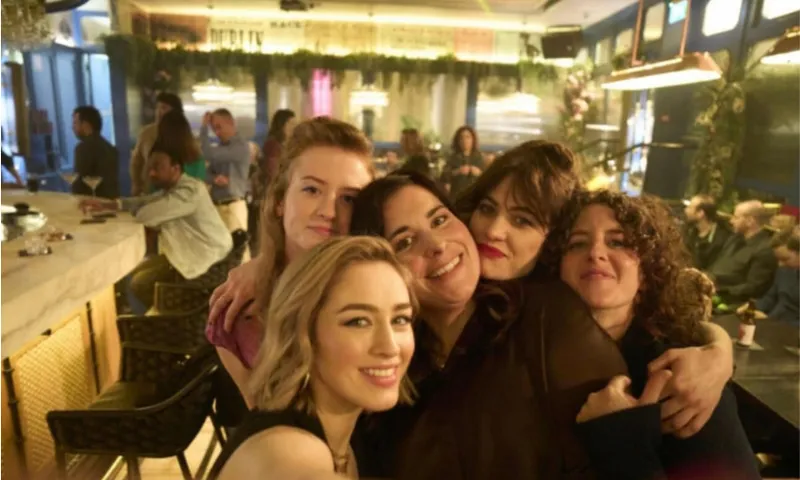 A photo of five young women all embracing in a pub.