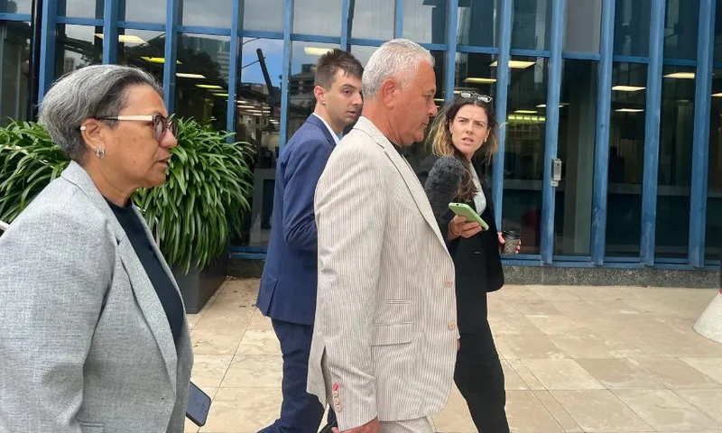 A side-on view of John Tamihere entering the high court flanked by journalists.
