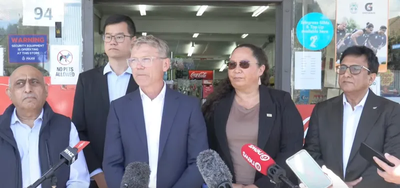 four men and one woman wear business attire and stand in front of microphones for an announcement
