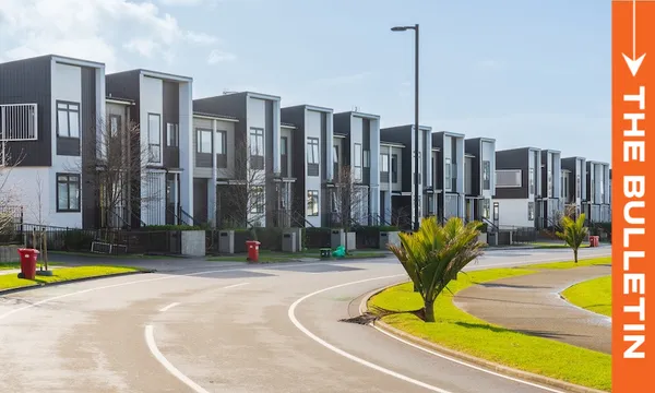 A row of modern, two-story townhouses lines a curved suburban street with green lawns, small palm trees, and red rubbish bins. A bright orange vertical banner reads "THE BULLETIN" on the right side of the image.