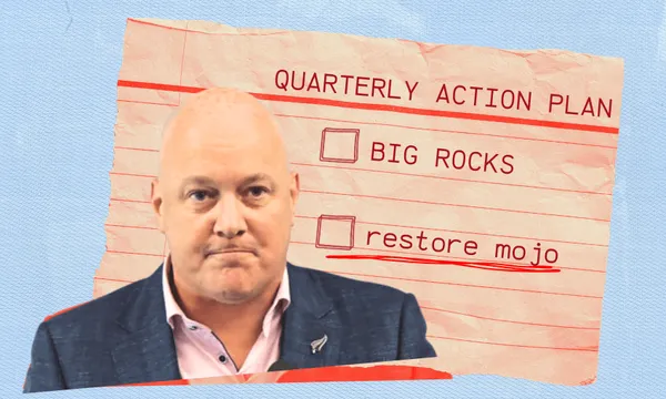 A bald man in a suit stands in front of a notecard labeled "Quarterly Action Plan" with checkboxes for "BIG ROCKS" and "restore mojo," the latter underlined in red. The background is blue and textured.