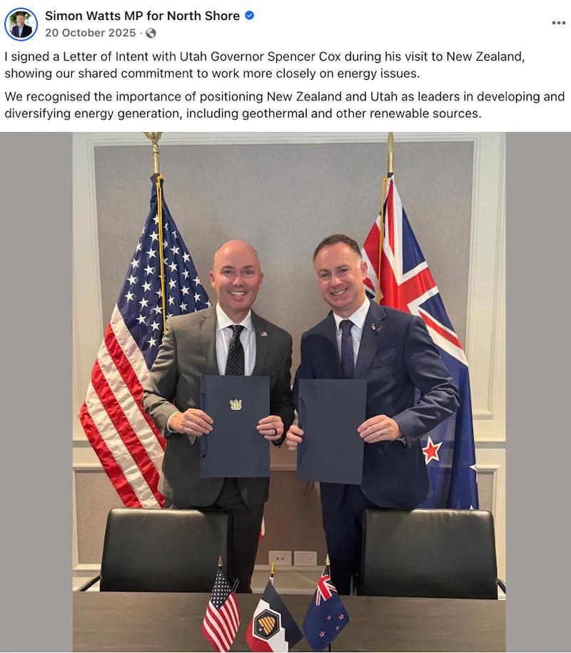 Two men in suits smile while holding signed documents in front of New Zealand and Utah flags. Small flags and a handshake ornament are on the table. A caption describes their commitment to cooperation on energy issues.