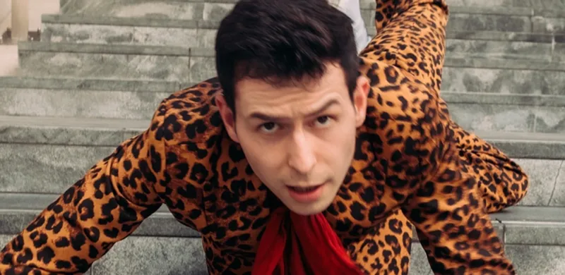A young man in a cheetah suit on looks as if he has fallen down the stairs and is look up at the camera.