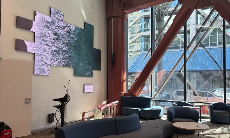 A photo of the inside of Te Matapihi, Wellington's central library, showing a large digital screen and large windows looking out over Harris St.