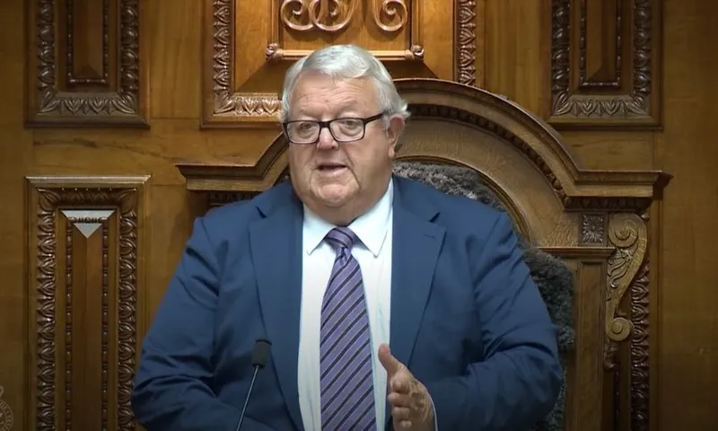 Gerry Brownlee stands in front of his chair while speaking in the chamber.