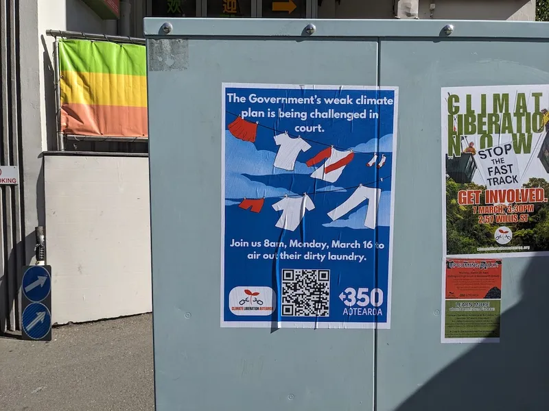 a poster on an electricity box of laundry hanging saying 'join us as the government airs out their dirty laundry'