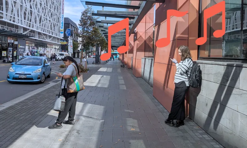 the footpath with a red toned building in the background and people standing around in Central Christchurch