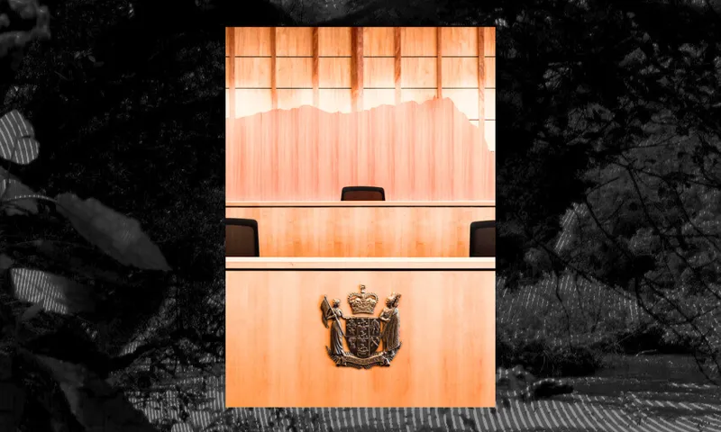 A wooden judge’s bench with an empty chair and a coat of arms emblem is seen in a courtroom, set against a backdrop of wooden paneling and windows.