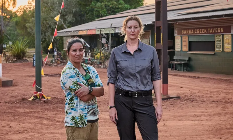 Dulcie and Eddie in a scene from Deadloch, standing in front of a dusty Australian pub
