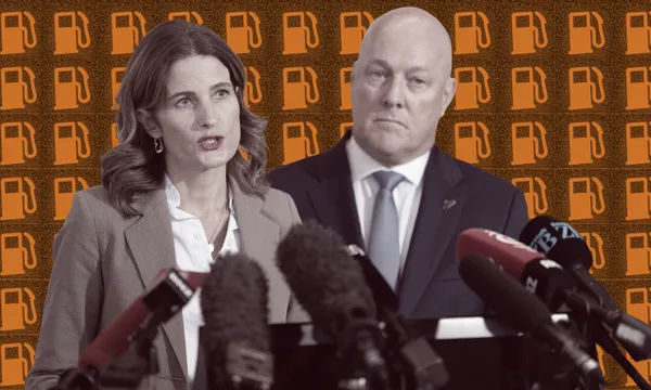 Two people stand in front of several microphones at a press event, with an orange background featuring repeated fuel pump icons.