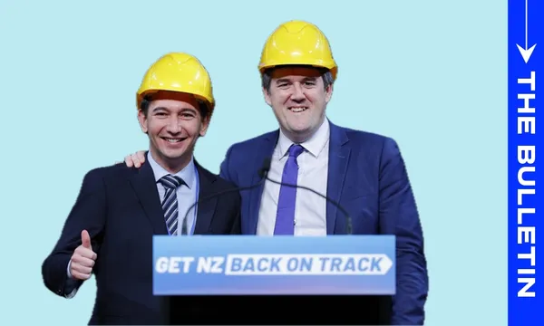 Two men in suits and yellow construction helmets stand smiling behind a podium that reads "GET NZ BACK ON TRACK." One man has his arm around the other, and the man on the left gives a thumbs-up. The background is light blue.
