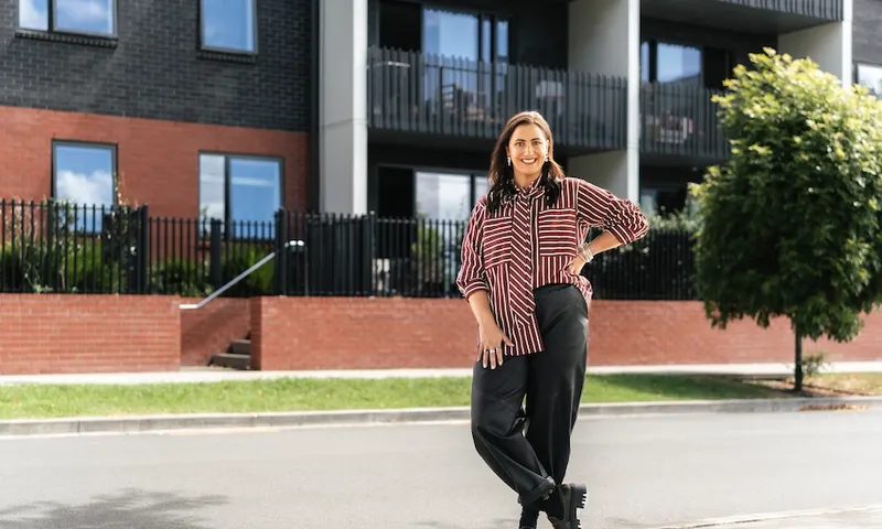 Hayley Sproull stands in front of a row of terraced townhouses, her hand on her hip