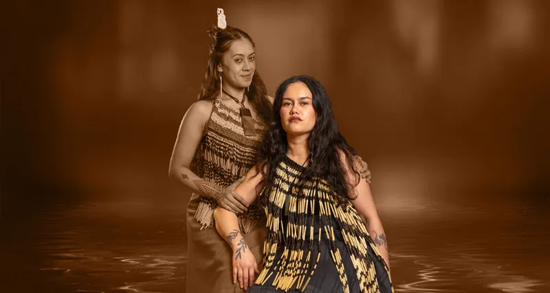 A production image of two wāhine Māori: one is seated and the other is standing at her shoulder, to indicate she is the tupuna.