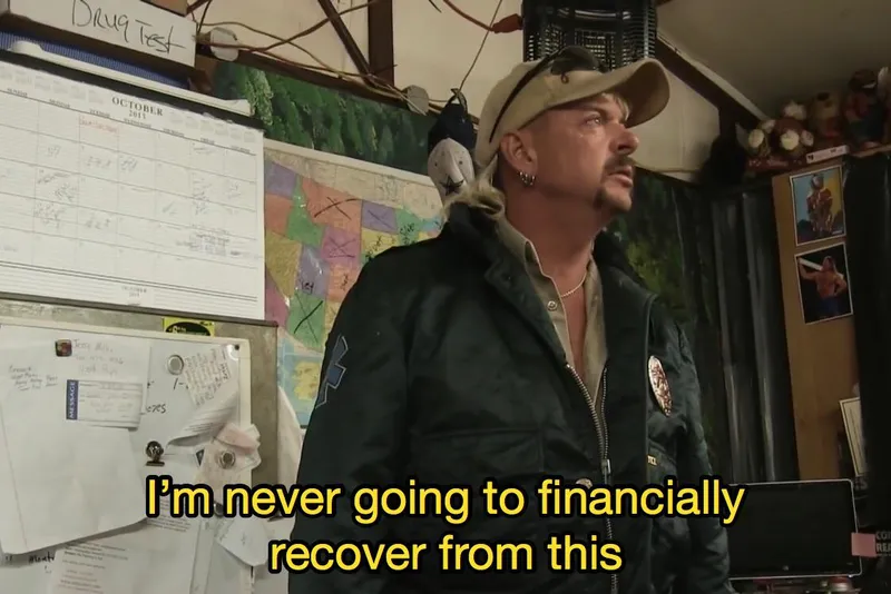 A man in a green jacket and khaki cap stands indoors near a cluttered bulletin board and calendar, looking serious. Yellow text at the bottom says, “I’m never going to financially recover from this.”.