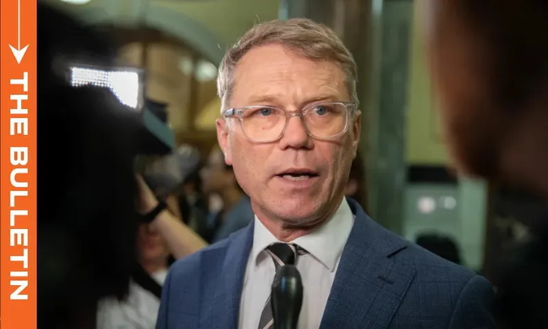a man with clear rimmed glasses and short hair talks to media