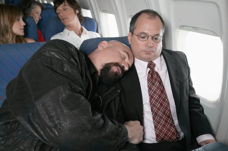 Businessman Sitting in an Aeroplane Trapped by a Man Sleeping by His Side