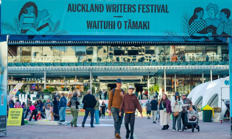 A large outdoor square with blue signage for a books festival and people walking through to an events centre