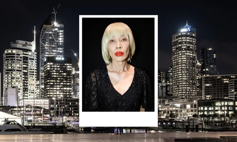 a model portrait of a woman with a bleached blonde bob and striking red lipstick. in the background a cityscape of downtown Auckland at night