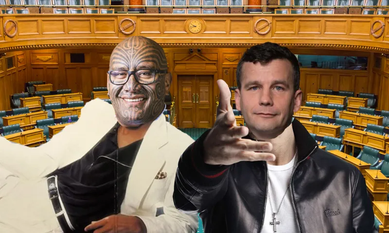 Two men pose in front of empty wooden parliamentary chamber seats; one wears a white suit and glasses with facial tattoos, the other wears a black jacket and gestures with his hand.