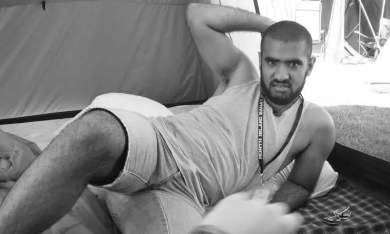 A black and white photo of Pax Assadi who is lying in a come hither position.