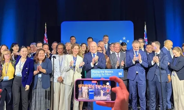 a large group of politicians wearing suits and blouses stand on a stage for a group photo