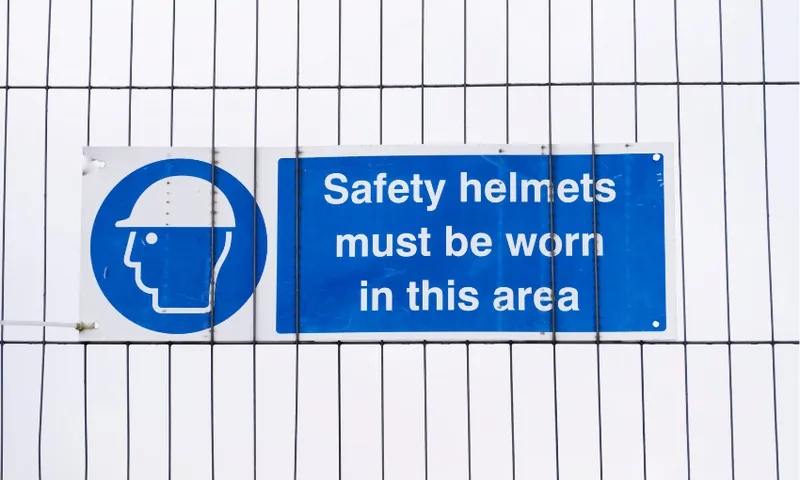 a construction fence with a sign instructing that safety equipment must be worn