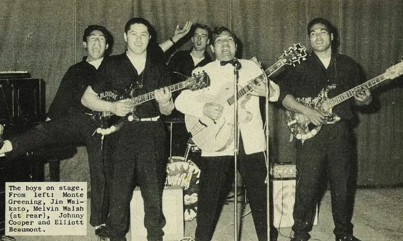 A vintage black-and-white photo shows five men playing guitars and singing on stage. Four are in front, one is at the back, and a piano is visible on the left. A caption identifies them as Monte Greening, Jim Waikato, Melvin Walsh, Johnny Cooper, and Elliott Beaumont.