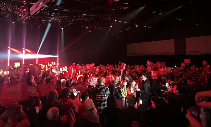 Hipkins and partner Toni Grace are flanked by supporters as they walk through the conference crowd.
